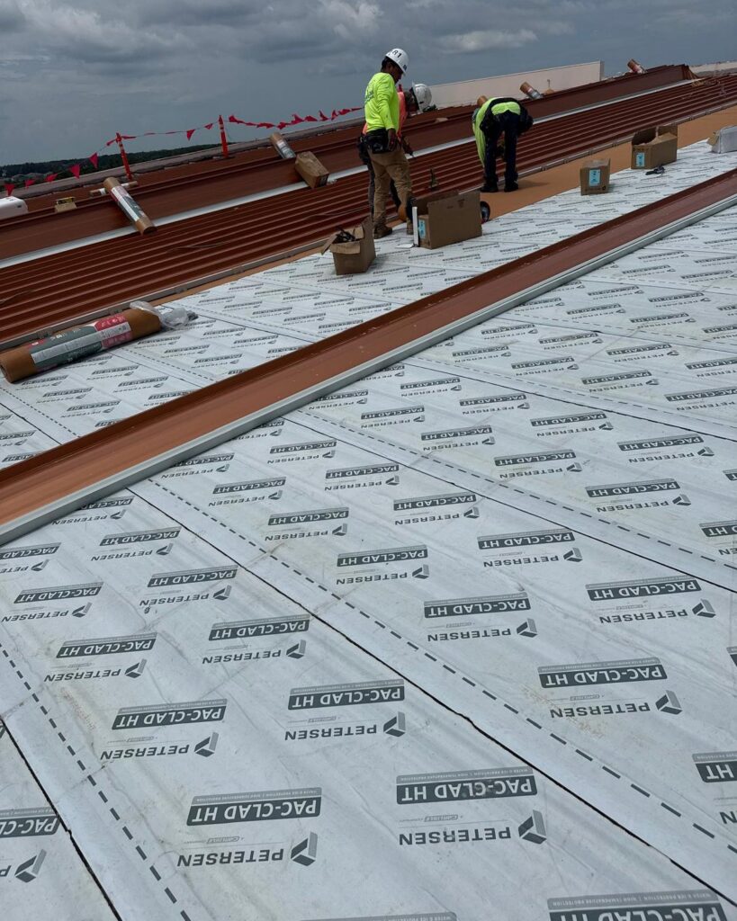 JHI Roofing crew installing a standing seam metal roof on a commercial building