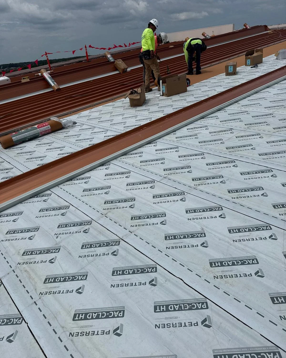 JHI Roofing crew installing a standing seam metal roof on a commercial building